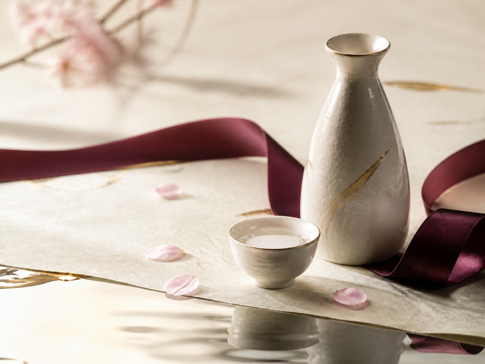 ひとひらの桜と徳利、盃が並ぶ和紙の上の静物